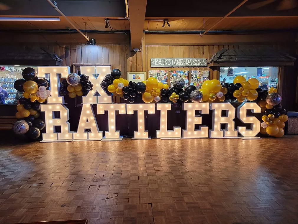 Balloons surrounding a "TX Rattlers" sign inside a wood-paneled lobby