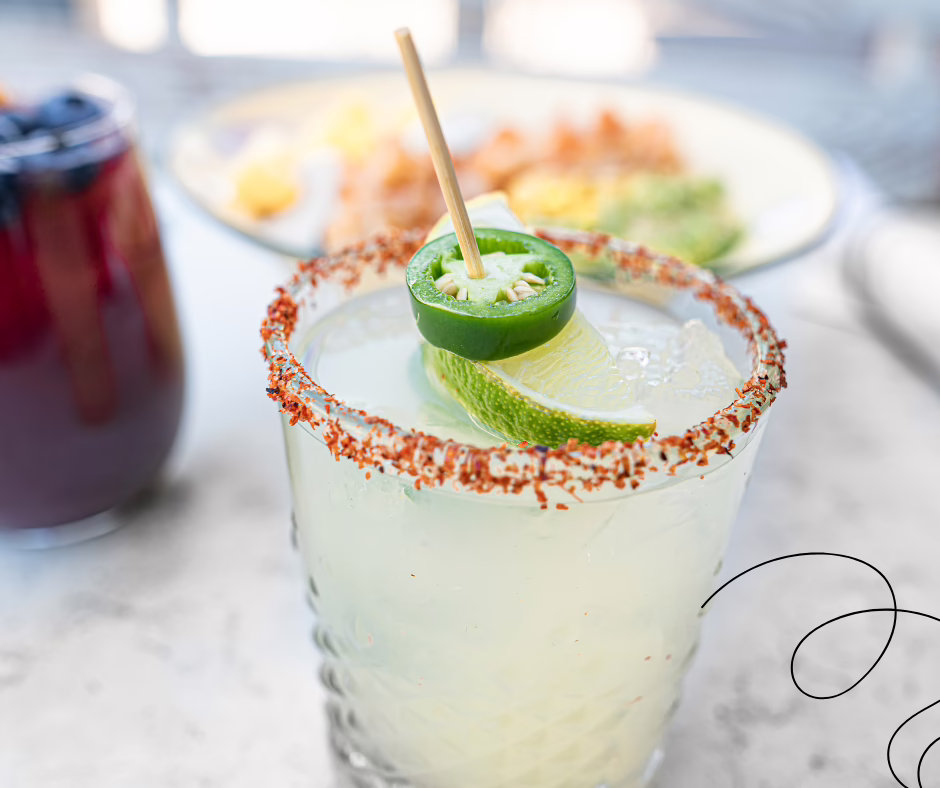 A close up of a margarita with a pepper and lemon stuck together by a tooth pick